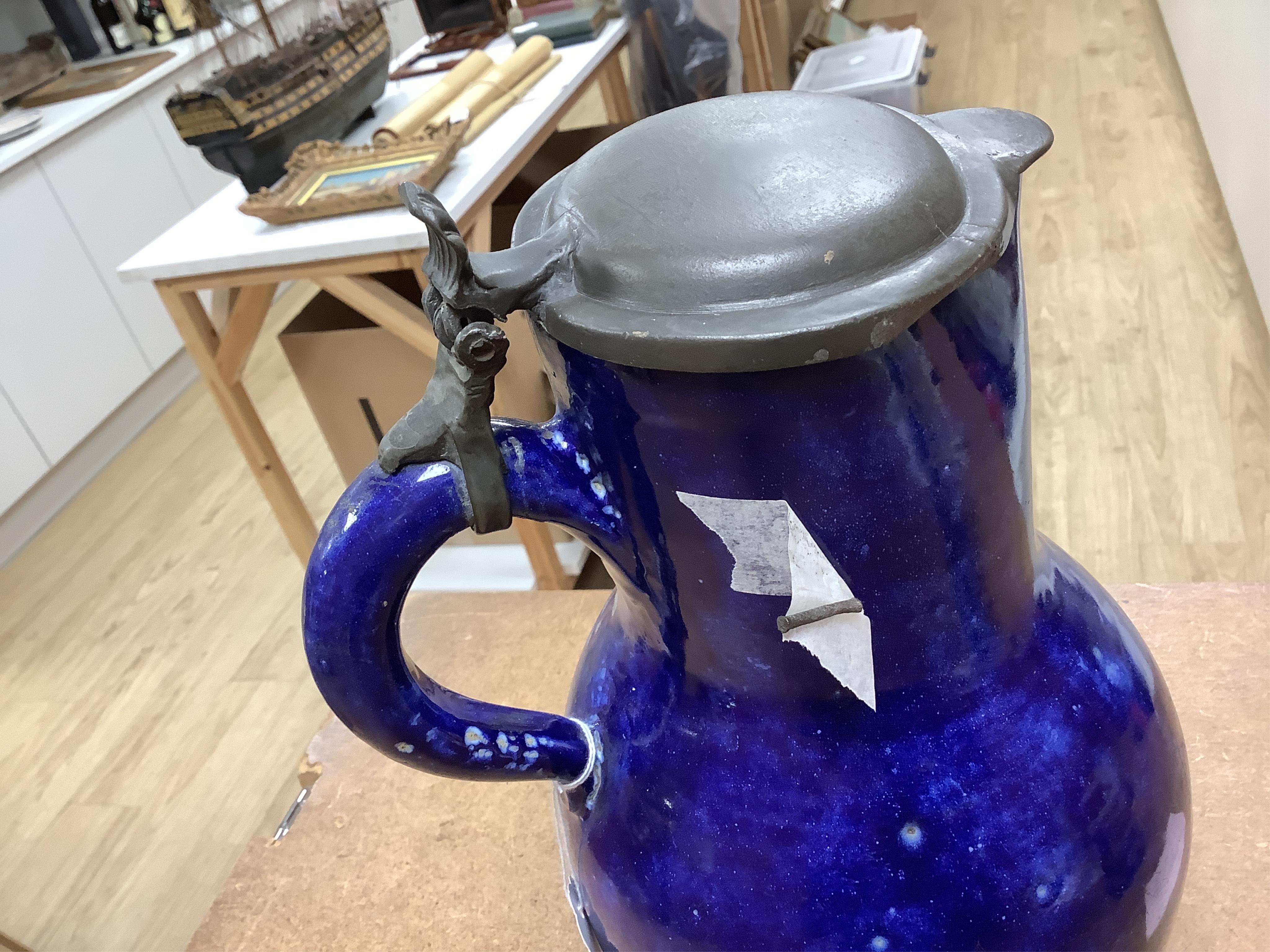 An 18th century German blue glazed faience jug with pewter lid, 30cm. Condition - poor to fair